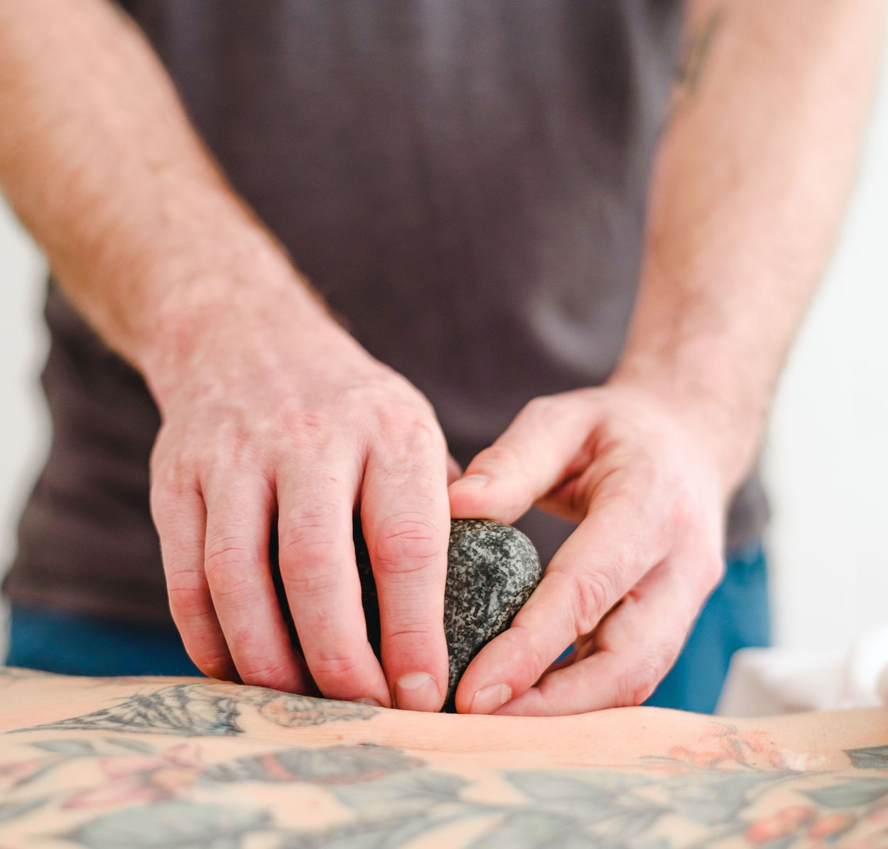 close up of Jon Dawson, RMT hand using hot stone during registered massage therapy